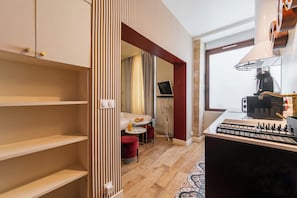A compact kitchen with a gas stove, a coffee machine, and a small dining area with a table and chairs.