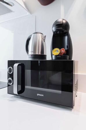 A black kitchen appliance with a kettle and coffee maker on top.