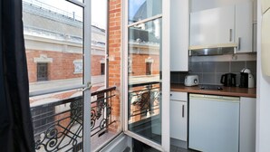 Cocina compacta con ventana, balcón y vista a un edificio de ladrillo.