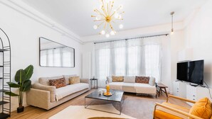 A modern living room with a sofa set, coffee table, TV, and a large plant.