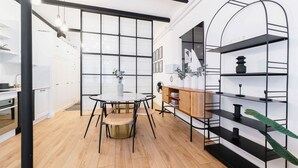 A modern kitchen with a round dining table, black metal shelving, and a large window.