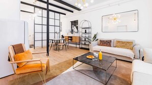 A modern living room with a sofa, armchair, coffee table, and dining area.