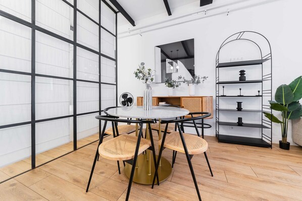 A modern interior with a round table, four chairs, a mirror, a black metal shelf, and a potted plant. - Confortable appartement equipe Sacre coeur - 4P (Paris)