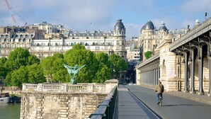 Eine Brücke mit einer Statue, einem Radfahrer und historischen Gebäuden im Hintergrund.