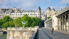 A bridge with a statue, a cyclist, and historic buildings in the background.