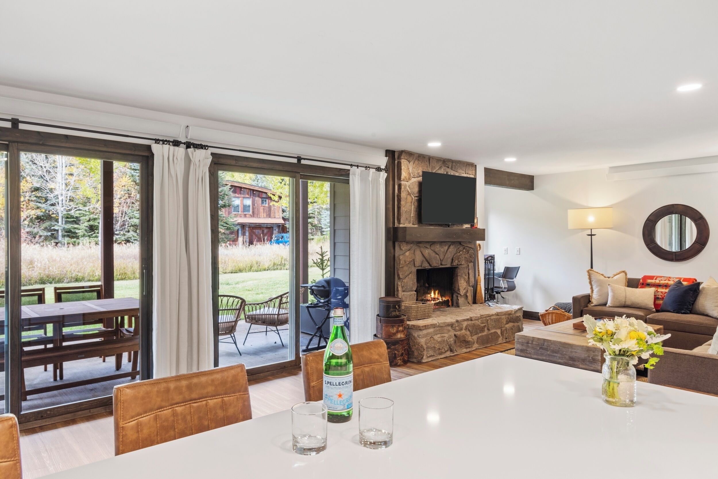 A spacious living room with a stone fireplace, a large dining table, and a cozy seating area.