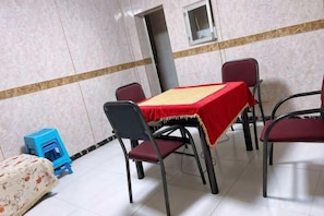 A dining area with a table covered in a red tablecloth, surrounded by chairs.