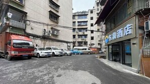 Een straat met geparkeerde auto's en een gebouw met een bord waarop 'Dongqiao Hotel' staat.