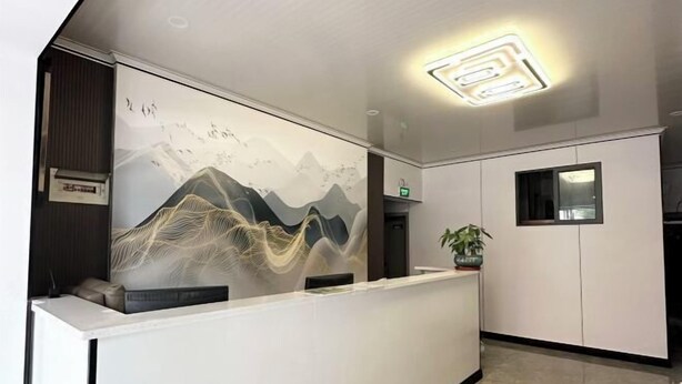 Een receptie met een modern design, met een receptiebalie, een wanddecoratie van bergen en een plafondlamp.