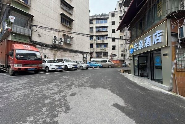 A street view with a row of parked cars and a red truck. There is a building with a sign that reads '东池酒店' (Dong Qi Hotel).