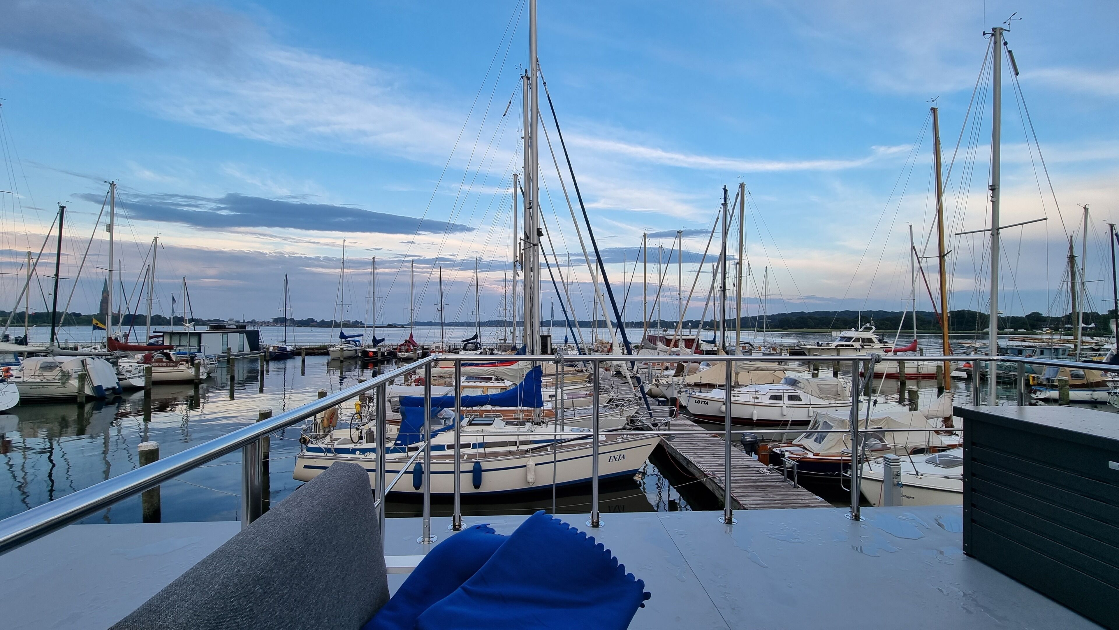 Un port de plaisance où sont amarrés de nombreux bateaux, un ciel dégagé et une vue sur l’eau.