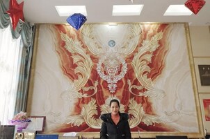 Una habitación con un tapiz grande y ornamentado en la pared, una cama con cabecera y una ventana con cortinas.