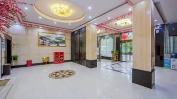 A hotel lobby with a reception desk, a large painting, and a circular decorative floor pattern.