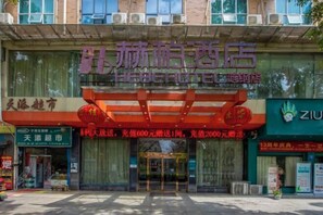 A hotel entrance with a prominent sign, a red awning, and a green storefront with signage. - Hebe Hotel (Loudi)