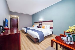 A hotel room with two beds, a desk with a computer, and a small table with water bottles.