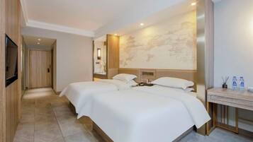A hotel room with two beds, a desk, and a television.