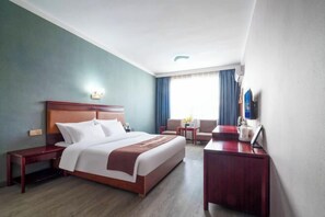 A hotel room with a large bed, a desk, a chair, and a small table. - Hebe Hotel (Loudi)