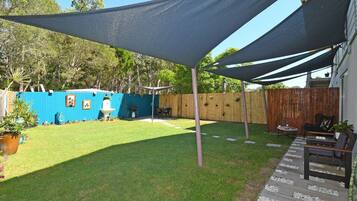 A backyard with a patio area, a blue fence, and a wooden fence.