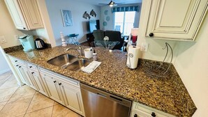Una cocina con encimeras de granito, electrodomésticos de acero inoxidable y muebles de cocina blancos.