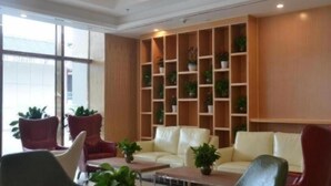A hotel lobby with a seating area, a wooden shelving unit with plants, and a large window. - Greentree Inn Guiyang Wudang District High-speed Railway East Station (Guiyang)