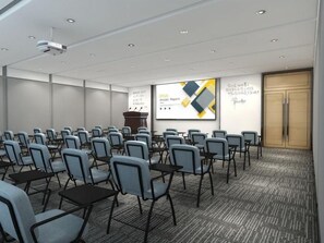 A conference room with rows of chairs and tables, a projector screen displaying a presentation, and a podium. - Greentree Inn Guiyang Wudang District High-speed Railway East Station (Guiyang)