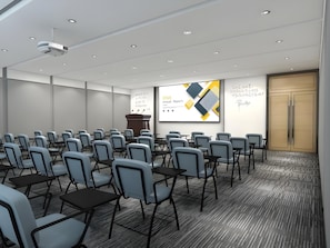 Un salón de conferencias con filas de sillas, un atril, una pantalla de presentación y una puerta.