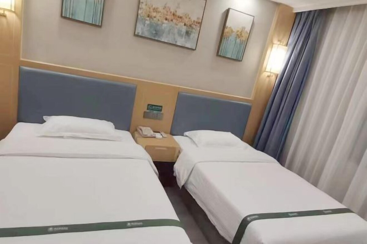 Habitación de hotel con dos camas, una mesita de noche y un teléfono instalado en la pared.