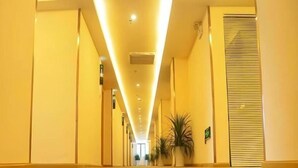 A hotel corridor with a long hallway, doors on both sides, and potted plants. - Greentree Inn Guiyang Wudang District High-speed Railway East Station (Guiyang)