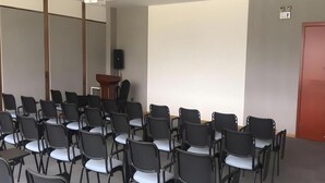 A conference room with rows of chairs, a podium, a projector, and a closed door. - Greentree Inn Guiyang Wudang District High-speed Railway East Station (Guiyang)