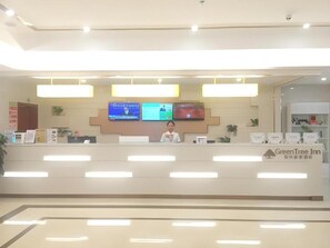 A reception desk with a digital display, a sign for GreenTree Inn, and a plant on the counter. - Greentree Inn Guiyang Wudang District High-speed Railway East Station (Guiyang)