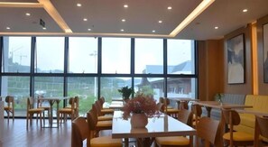Un'elegante sala da pranzo moderna con ampie finestre, arredi in legno e un tavolo centrale con un vaso.