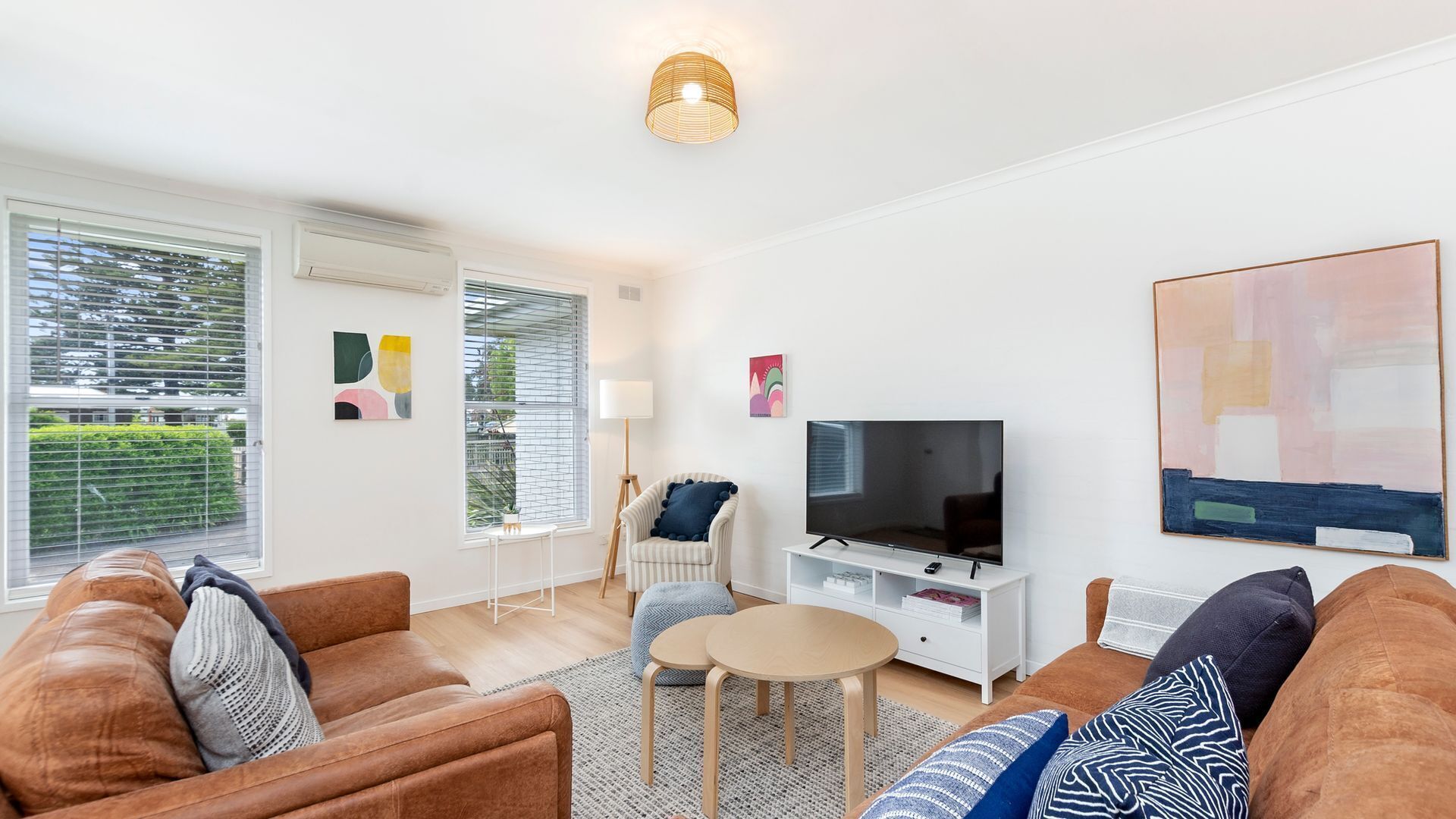 A modern living room with a sofa set, a television, and artwork on the walls.