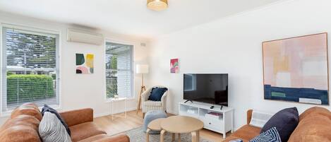 A modern living room with a sofa set, a television, and artwork on the walls.