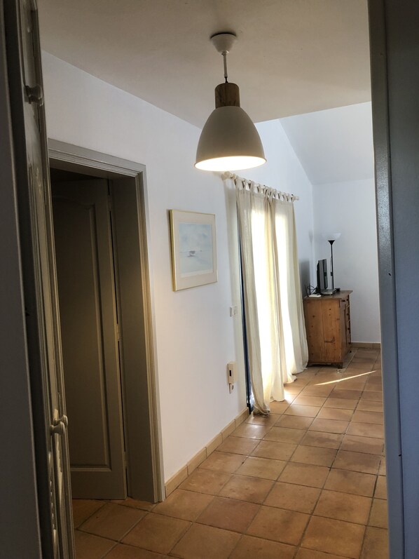 A hallway with a ceiling fan, a wooden cabinet, and a door.