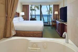 A hotel room with a large bed, a TV, a desk, and a view of the ocean. - On Beautiful Waikiki Beach! Pool, Spa, 3 On-Site Restaurants, Water Activities (Honolulu)