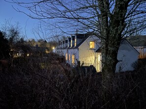 Una casa residencial con una chimenea visible, rodeada de maleza.
