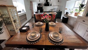 A dining area with a wooden table set for four, surrounded by leather chairs. A vase with flowers is placed in the center. - No 4 old Post Office Row, Isle of Skye (Skeabost)
