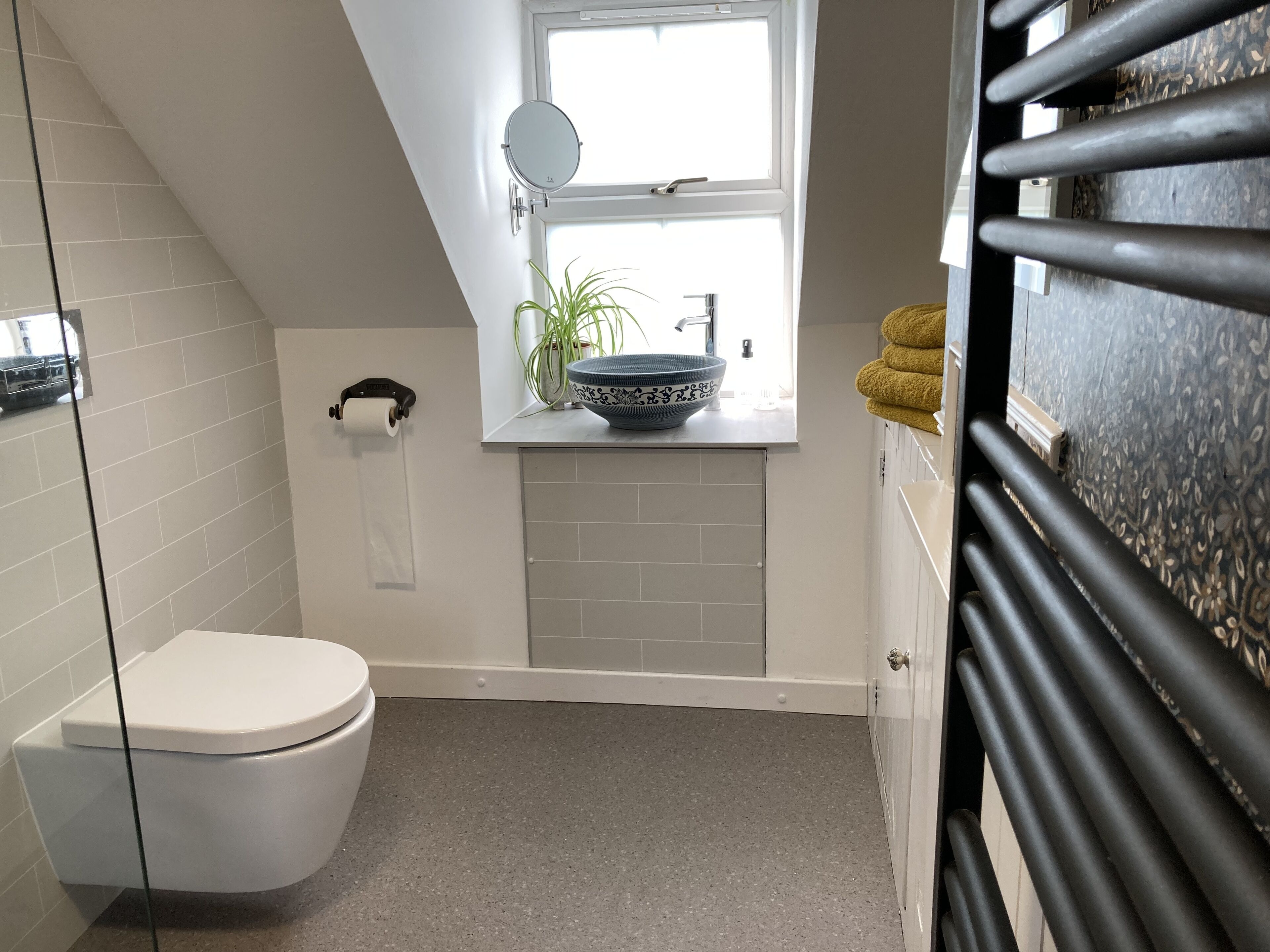 A bathroom with a toilet, a sink with a mirror, and a window.