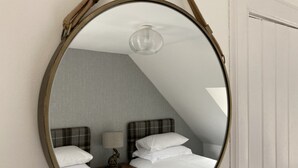 A bedroom with a bed, two bedside tables, a lamp, and a mirror. - No 4 old Post Office Row, Isle of Skye (Skeabost)
