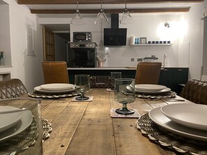 Comedor con una mesa de madera dispuesta para cuatro personas, rodeado de sillas de cuero.
