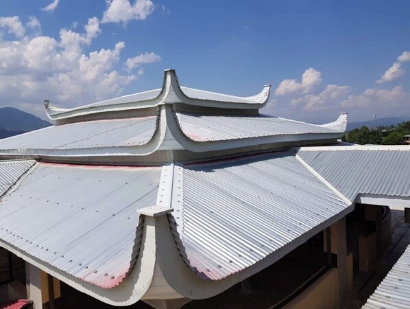 Traditional architecture with a tiered roof and overlapping eaves, set amidst a scenic backdrop of distant mountains.