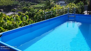 A rooftop swimming pool with a metal ladder, surrounded by lush greenery and a clear blue sky. - House with nice space near everything (Câmara de Lobos)