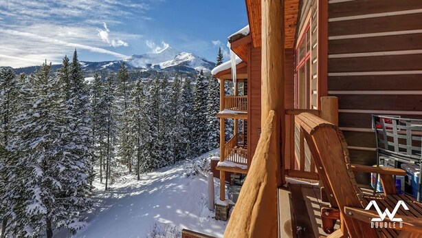 A wooden cabin with a balcony overlooking a snowy mountain landscape. - Luxurious King en Suites in a Pristine Penthouse! (Big Sky)