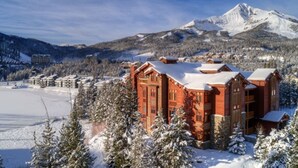 A lodge with a wooden exterior, surrounded by snow-covered trees and a mountain in the background. - Luxurious King en Suites in a Pristine Penthouse! (Big Sky)