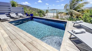 A pool area with lounge chairs, a wooden deck, and a view of the sea. - Villa Little Paradise - BIG DISCOUNT MARCH - APRIL !! (Collectivity of Saint Martin)