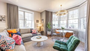 Un salon moderne comprenant un canapé, un fauteuil vert, une table basse ronde et un coin repas avec une table et des chaises.
