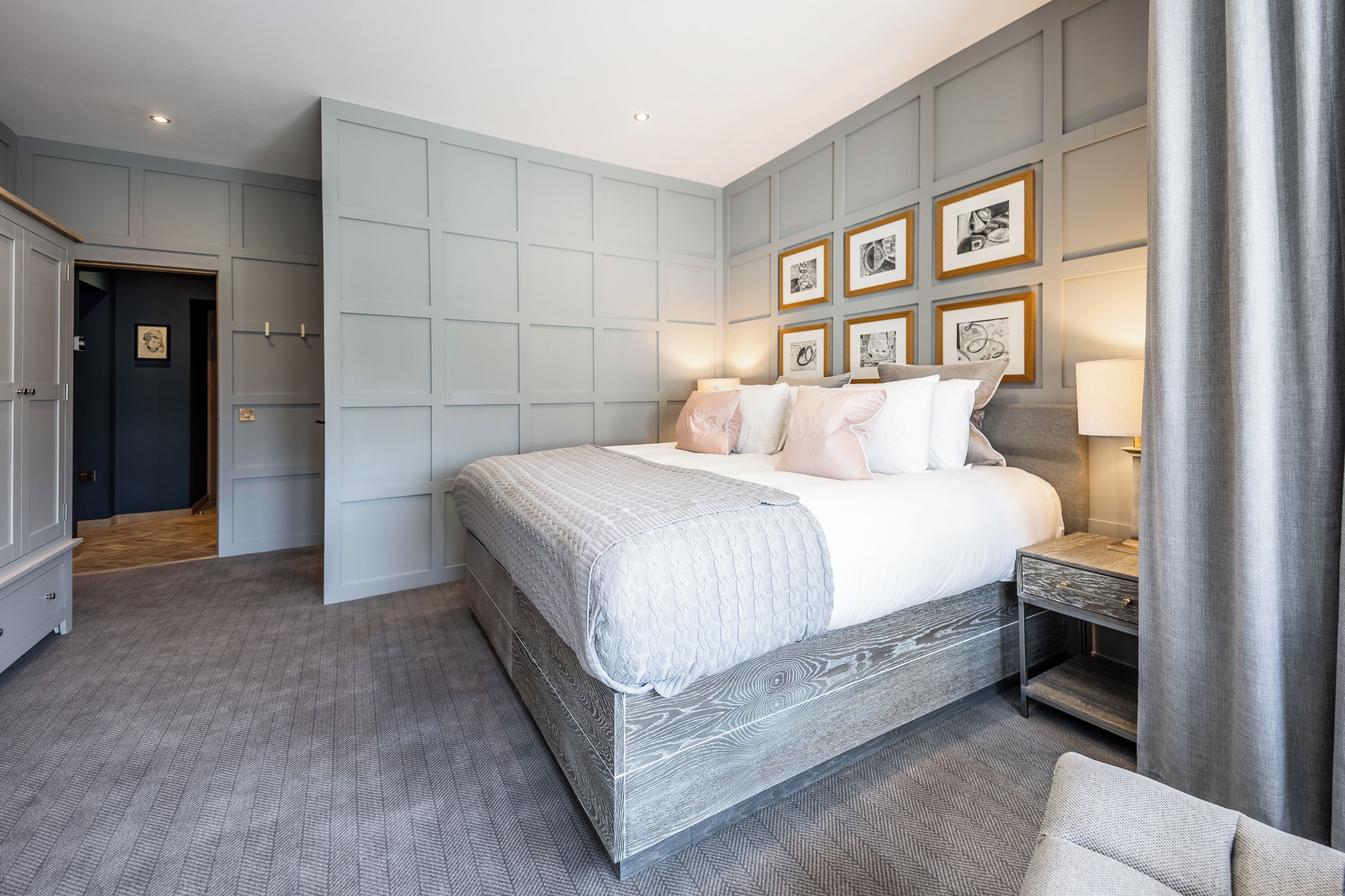 A modern bedroom with a large bed, a nightstand, and a wardrobe.