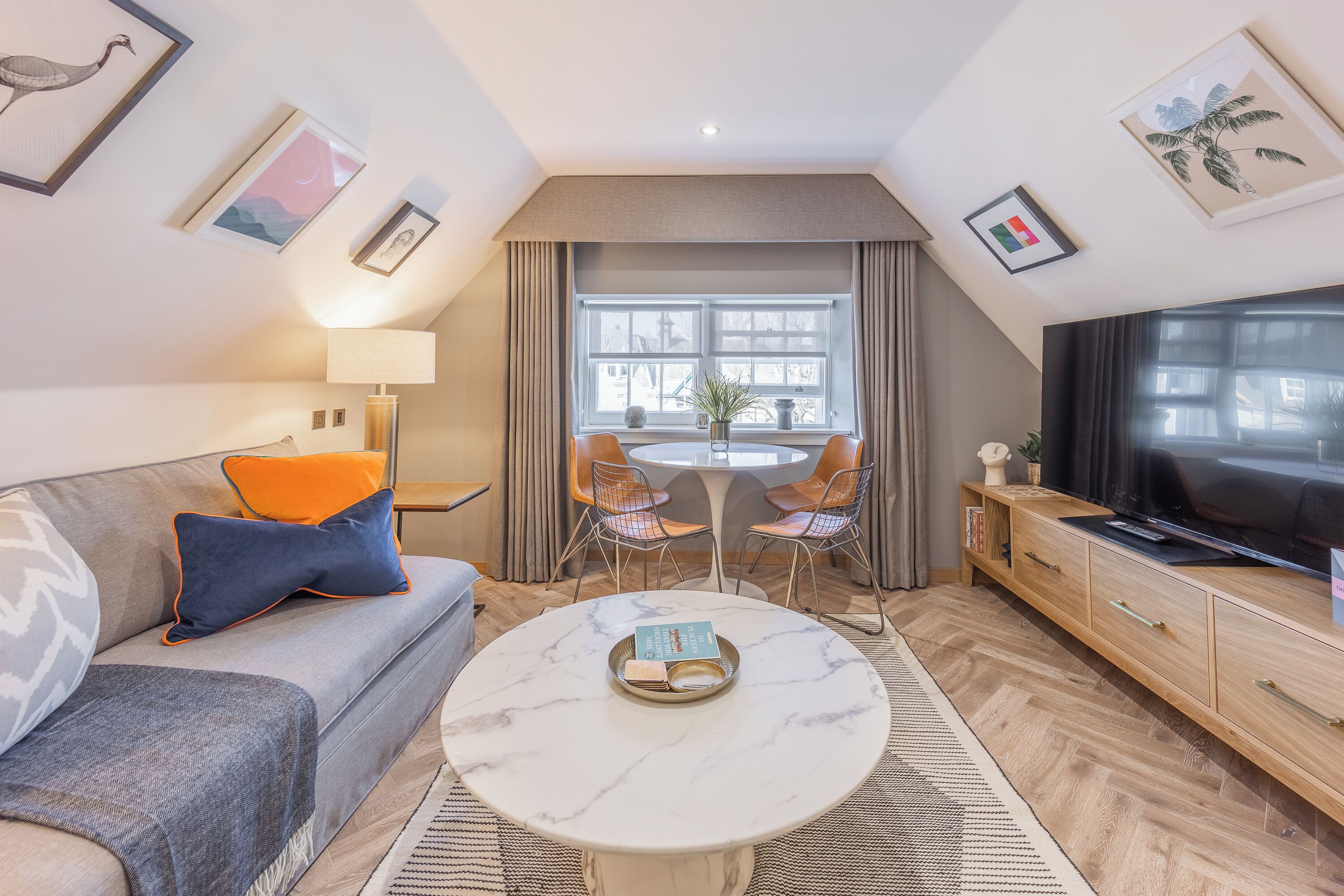 Een moderne woonkamer met een bank, salontafel, televisie en een eethoek.