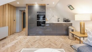 Une cuisine moderne dotée d’un four et d’un micro-ondes encastrés, d’un plancher en bois et d’un coin repas avec une table et des chaises.