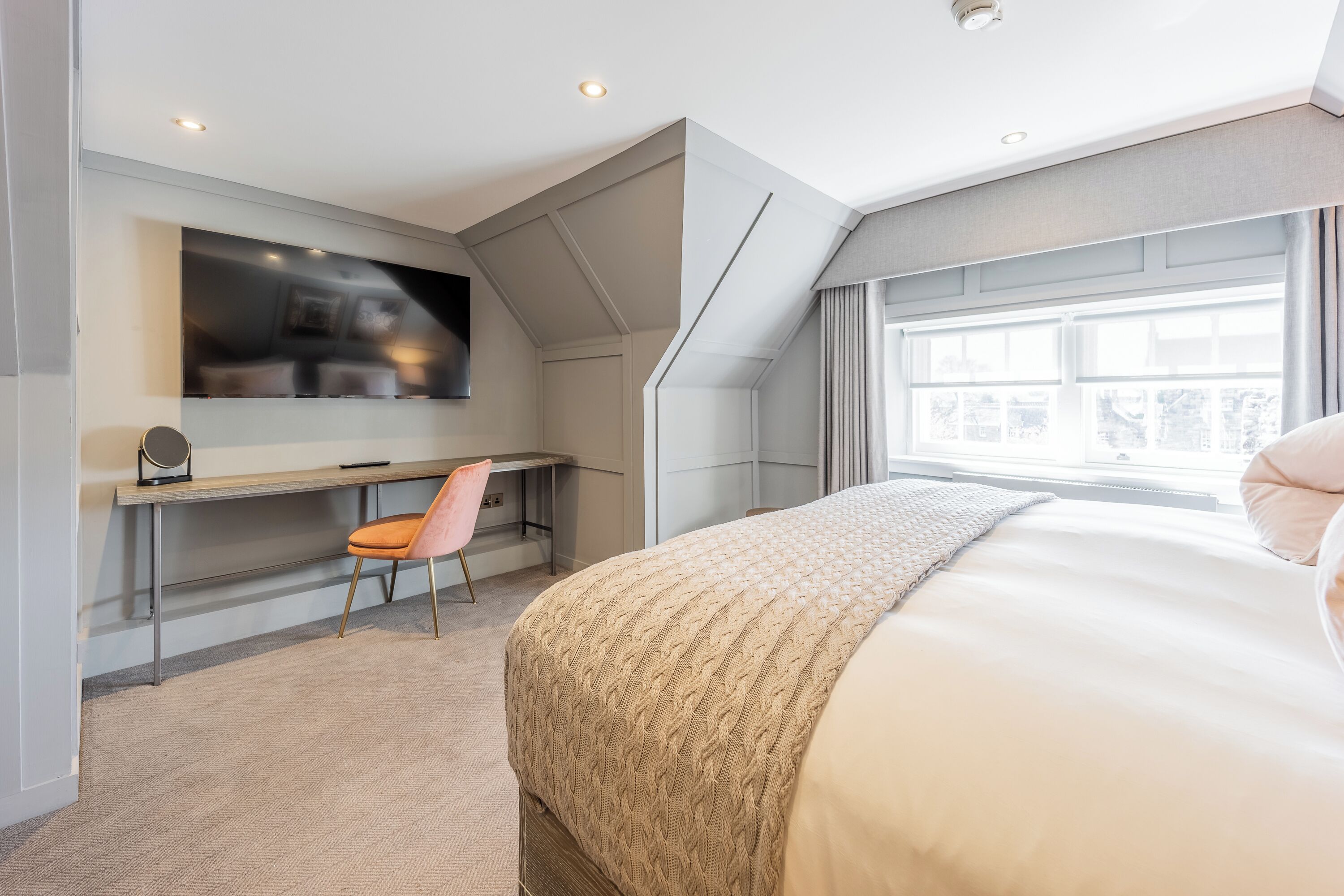 Un dormitorio moderno con una cama grande, un escritorio y una silla.